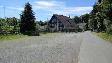 Un bâtiment à deux étages, doté d’un toit en pente, d’une enseigne indiquant qu’il s’agit d’un hôtel, et d’un chemin de gravier devant l’entrée.