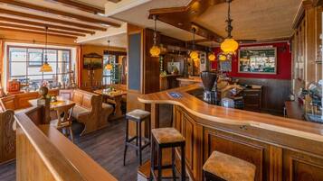 A bar area with wooden bar stools, a counter, and hanging pendant lights.