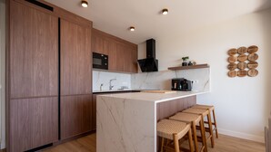 Una cucina moderna con mobili in legno, un'isola in marmo, sgabelli da bar e una macchina per il caffè.