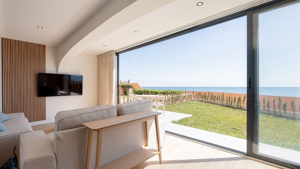 Un soggiorno moderno con un'ampia porta-finestra che si apre su un balcone vista mare.