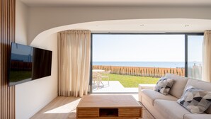 Un soggiorno moderno con una grande TV, un divano, un tavolino da caffè e vista mare.