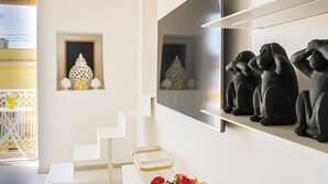 Un interno moderno con una scala, una TV a parete e elementi decorativi come una lanterna e sculture.
