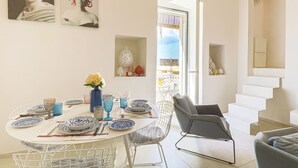 Un'area pranzo con un tavolo rotondo, sedie e un vaso di fiori.