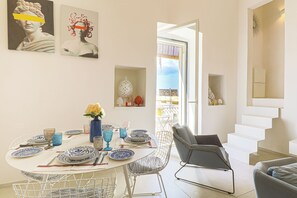 Un coin repas avec une table ronde, des chaises et un vase de fleurs.