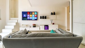 Un soggiorno moderno con un divano, una televisione a schermo piatto, una scala e un'arredamento minimalista.