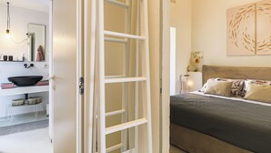 Una stanza con un letto, un comodino, uno specchio, un lavandino e una porta.
