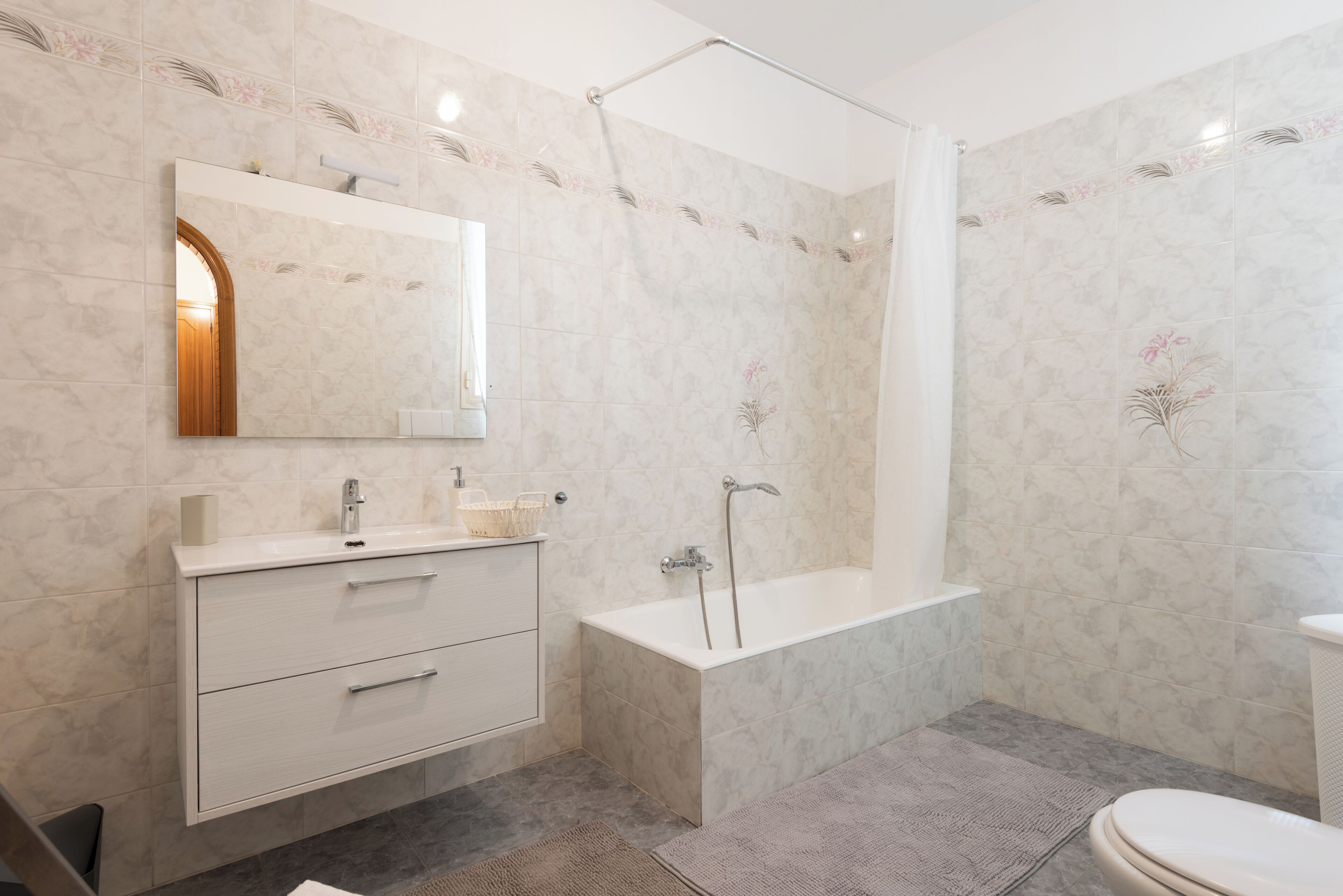 A modern bathroom with a white vanity, a freestanding bathtub, and a shower enclosure.
