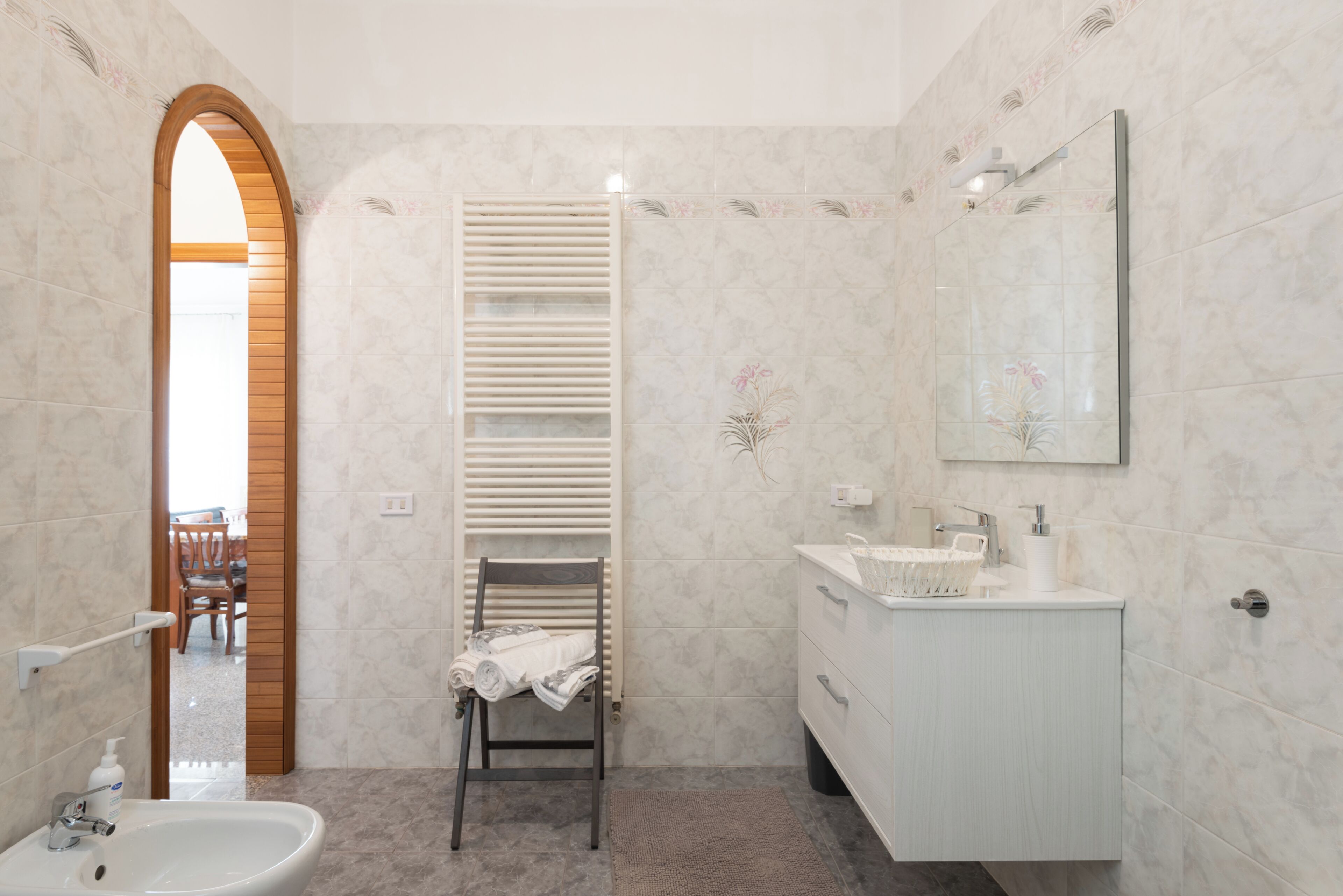 Un baño con lavamanos, espejo, toallero y zona de ducha.