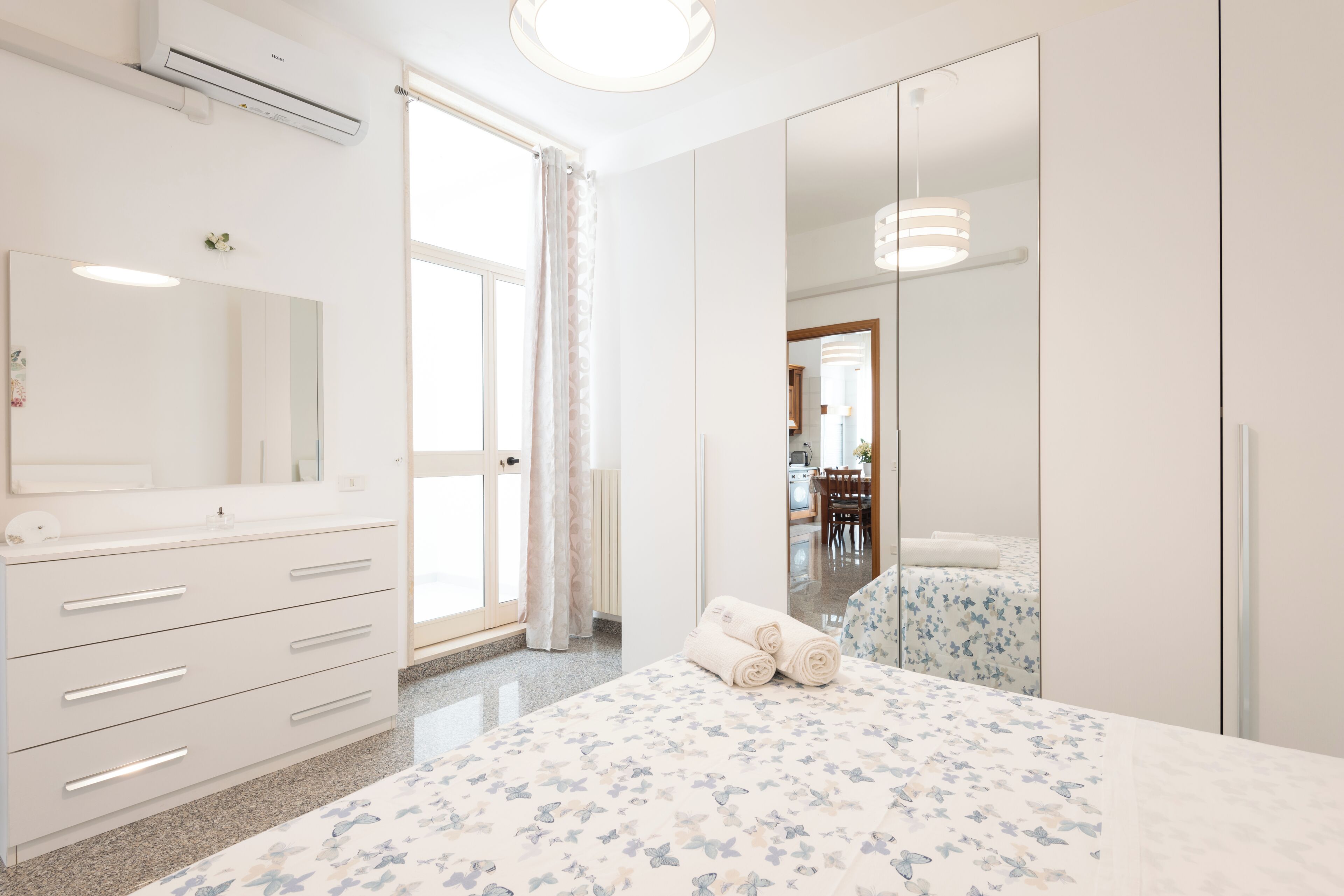 A bedroom with a bed, a dresser, a mirror, and a wardrobe.