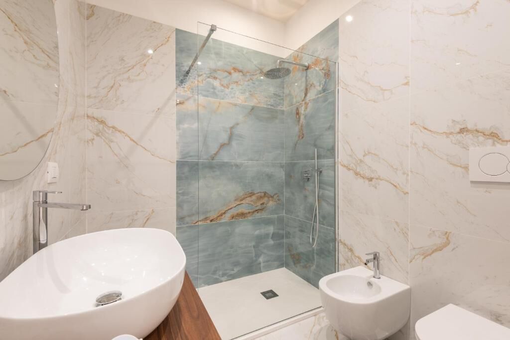 Ein modernes Badezimmer mit einer gläsernen Duschkabine, einem großzügigen freistehenden Waschbecken und einem Standbidet.