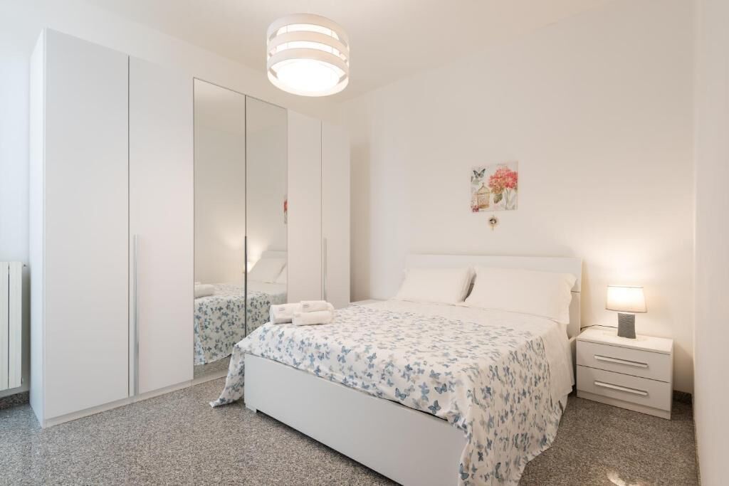 Un dormitorio con cama, mesita de noche, espejo y armario.