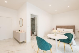 A modern bedroom with a bed, bedside table, and a small table with chairs.