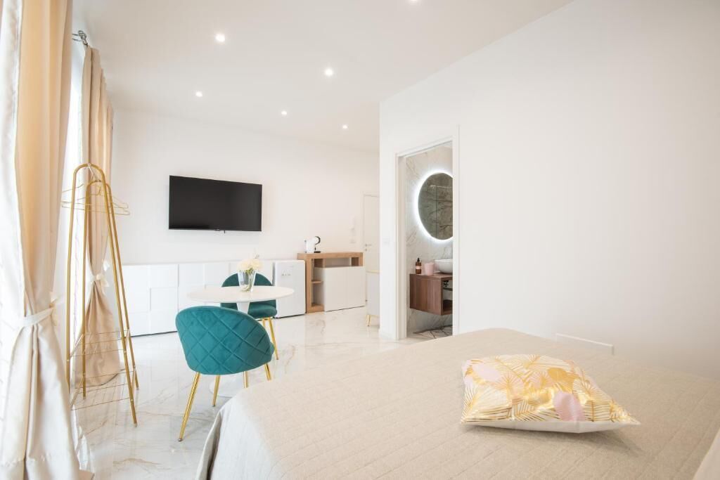Una habitación de hotel moderna con cama, escritorio, silla, televisor y baño.