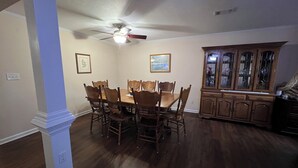 A dining room with a wooden table and chairs, a ceiling fan, and a wooden cabinet with glass doors. - Restful ranch, 4.6 miles from The Masters. 3-bedroom house, 2 full baths (Martinez)