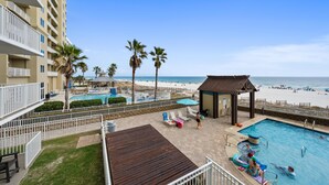 Un espace piscine d’hôtel avec vue sur la plage, comprenant une piscine, des chaises longues et un petit pavillon.