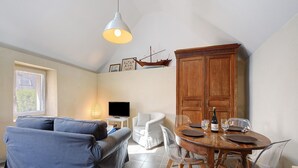 Un salon comprenant un canapé, une table à manger avec des chaises, un téléviseur et un meuble en bois.