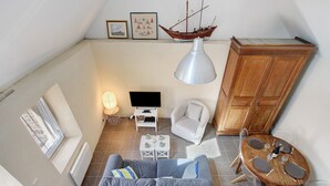 Un espace de vie de style loft comprenant un canapé, une table à manger et une maquette de bateau accrochée au mur.