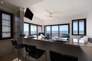 Eine moderne Küche mit Barbereich, großen Fenstern und Meerblick.