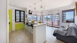 Uma cozinha moderna com uma ilha central, banquetas de bar e uma área de jantar com pratos amarelos.