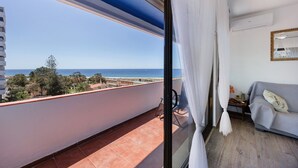 Uma varanda com vista para o mar, um sofá e um aparelho de ar condicionado.