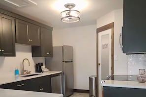A kitchen with dark cabinets, a stainless steel refrigerator, a sink, and a glass-top table. - "The Amber House" : The Perfect Beach Vacation Home (corpus christi)