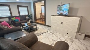 Una sala de estar con sofá, mesa de centro, televisor y aparador.