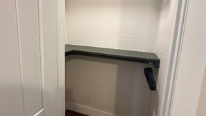 Un pasillo estrecho con una puerta blanca a la izquierda y una estantería verde a la derecha.