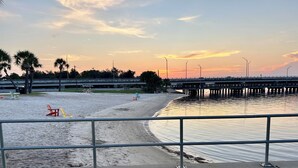 A beach with a pier, chairs, and a railing. - 3-bedroom house in tranquil Lynn Haven, beautiful sunsets, & minutes to PCB. (Lynn Haven)