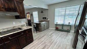 A spacious kitchen with dark wooden cabinets, a marble countertop, and a central island. - 3-bedroom house in tranquil Lynn Haven, beautiful sunsets, & minutes to PCB. (Lynn Haven)