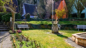 Un jardin avec un sentier, des bancs et une fontaine.