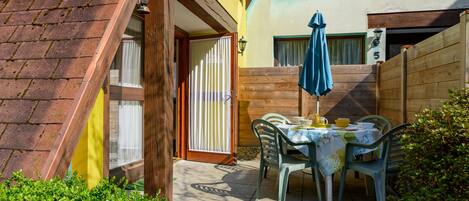 Un patio con una mesa y sillas, una cerca de madera y un edificio con un letrero con el número 5.