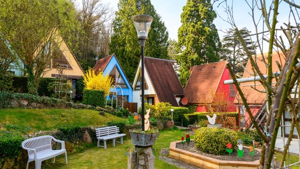 Un jardin avec un banc blanc, un lampadaire en métal et une variété de plantes.