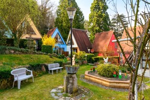 A garden with a white bench, a metal lamp post, and a variety of plants. - Gite Gewurz – Kaysersberg vineyard, parking and terrace (Kaysersberg Vignoble)