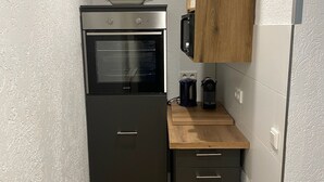 Eine kleine Küche mit Backofen, Mikrowelle und einer Holzarbeitsplatte.
