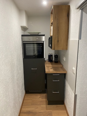 Eine kleine Küche mit Backofen, Mikrowelle und einer Holzarbeitsplatte.