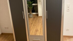 Ein Kleiderschrank mit zwei Türen und einem Spiegel in der Mitte.