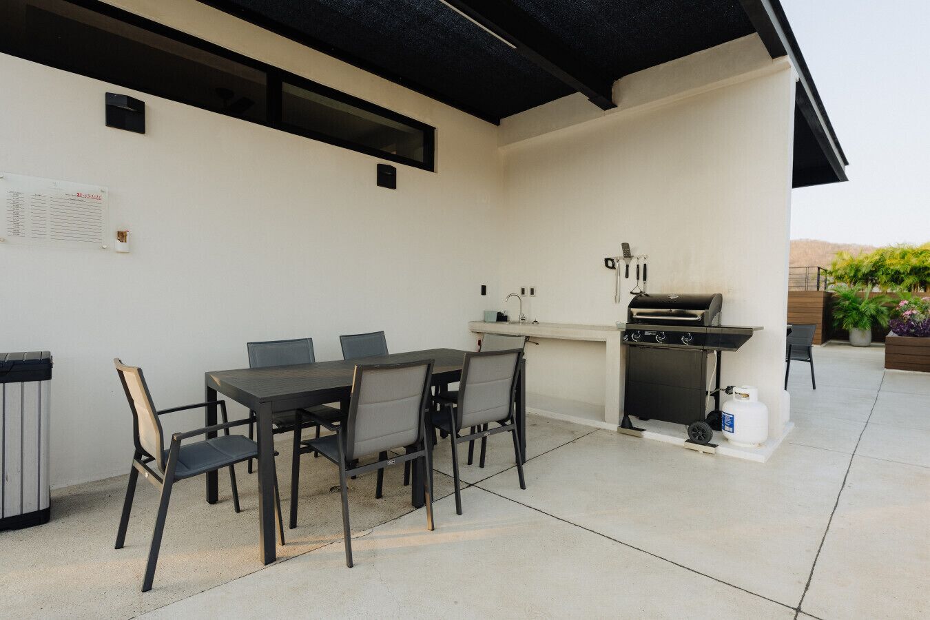Une terrasse extérieure avec une table et des chaises, un barbecue et un petit coin cuisine.