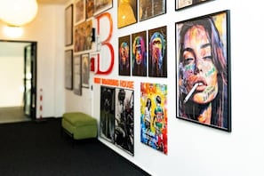 Pared com vários cartazes e uma grande letra 'B' vermelha.