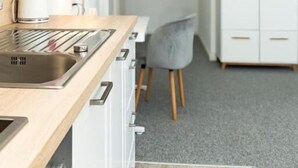 Eine moderne Küche mit Holzarbeitsplatte, Spüle aus Edelstahl und weißen Schränken.