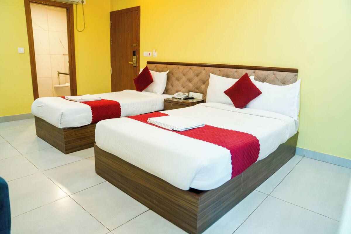 A hotel room with two beds, a wooden headboard, and a bathroom with a shower.
