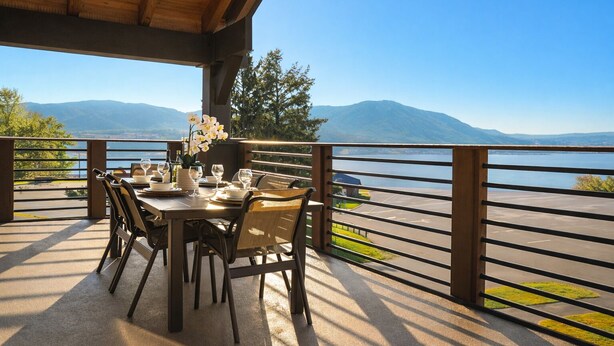 A dining area with a table set for four, overlooking a lake with mountains in the background. - Views+Pool+Hot tub: Summer Lake Days Made Easy at WorldMark Chelan – Lake House (Chelan)