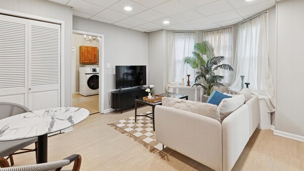 Una sala de estar moderna con un sofá, una televisión, una mesa de centro y un comedor con una mesa y sillas.