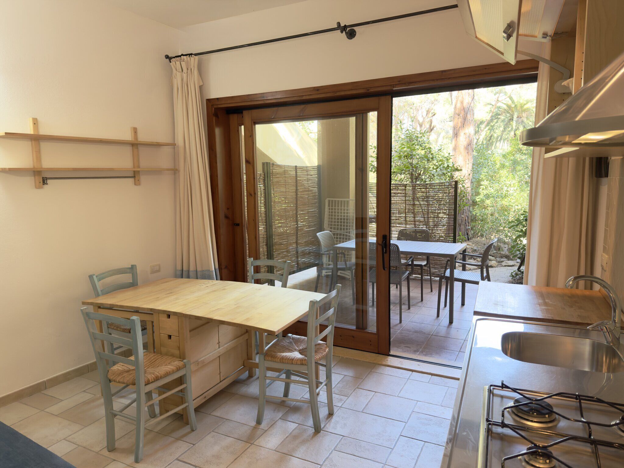 A compact kitchen with a dining area, a sliding glass door leading to an outdoor patio, and a gas stove.