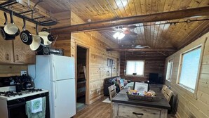 Uma cabana com cozinha equipada, incluindo fogão, geladeira e panelas penduradas.