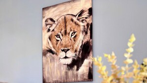 Ein Wohnzimmer mit einer Couch, einem Löwenbild und einer Topfpflanze.