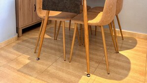 Ein Essbereich mit einer Holzkommode, Gläsern, einem Tigergemälde und gepolsterten Stühlen.