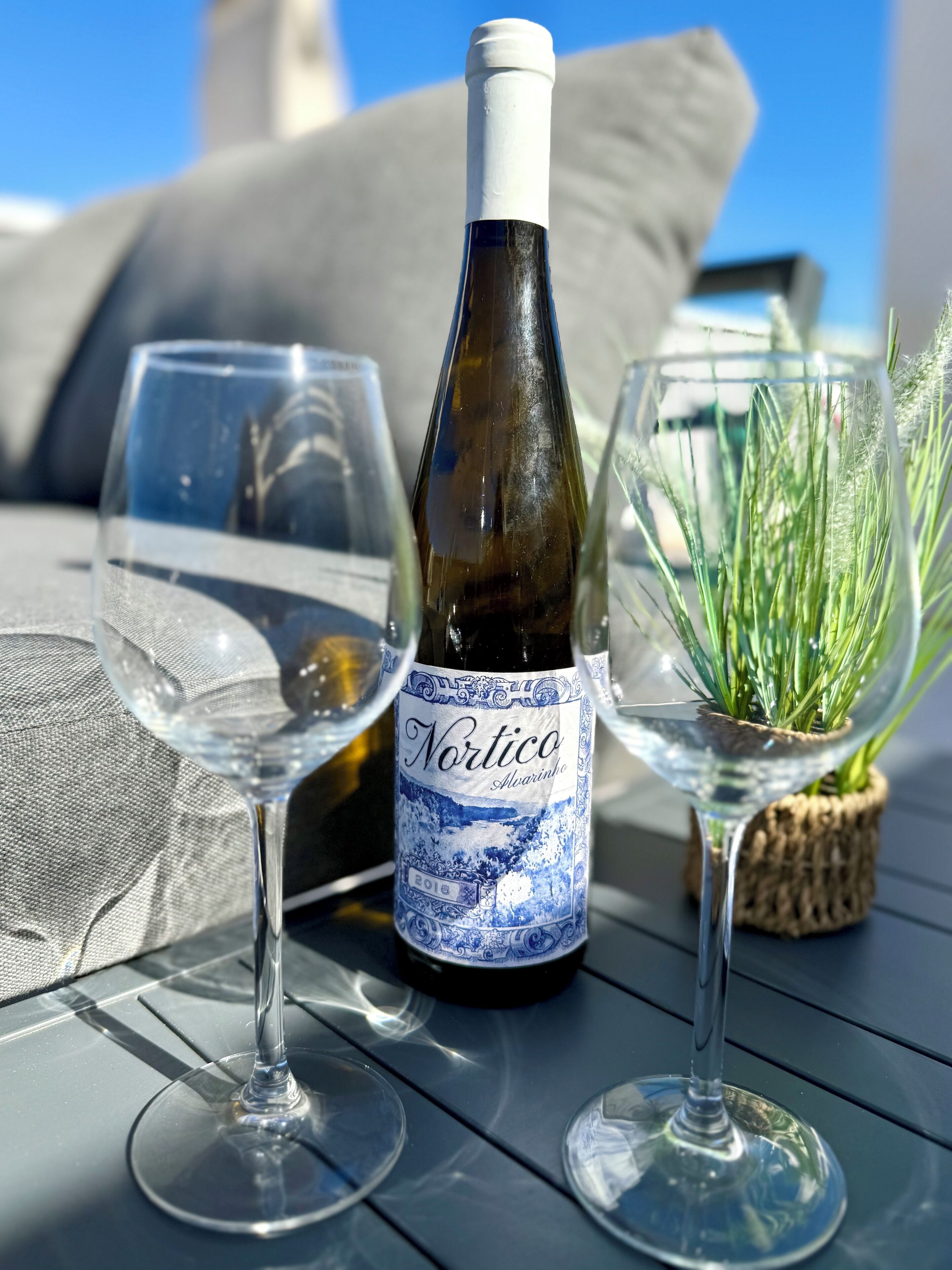 Une bouteille de vin, deux verres à vin et une petite plante sur une table en bois.
