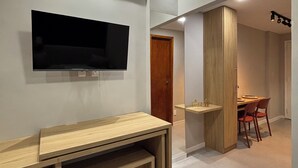 Een modern interieur met een wandtelevisie, een houten bankje en een eethoek met stoelen en een tafel.