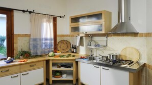 Une petite cuisine équipée d’une cuisinière à gaz, d’un évier et d’une fenêtre avec un rideau.