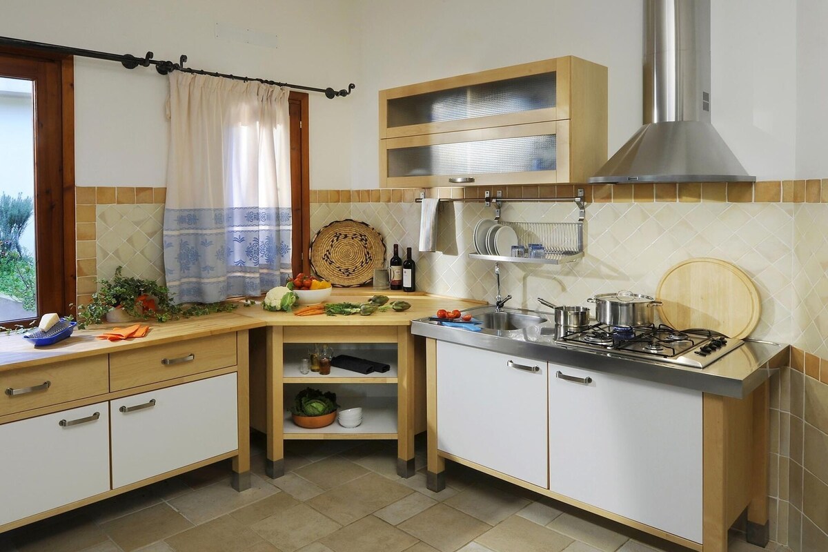 Una cucina compatta con fornello a gas, un lavandino e una finestra con tenda.